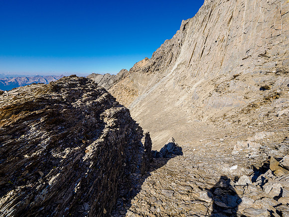 Descending the traverse across the SW face under summit cliffs.