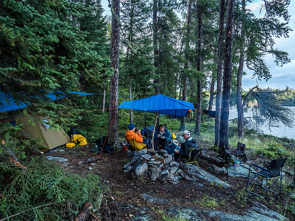 Niko, Dylan and Bill sit under the tarp at camp.