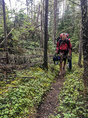 Jon on a wet 250m portage between Glenn and Optic.