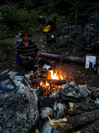 Hentie reads his book by a cheerful camp fire.