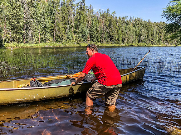 Harold launches his canoe in less than ideal muck.