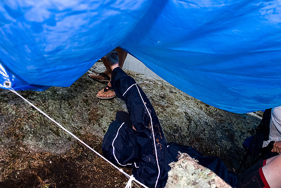 Rod helps Jon get back under the tarp after emptying the boats of rain water.