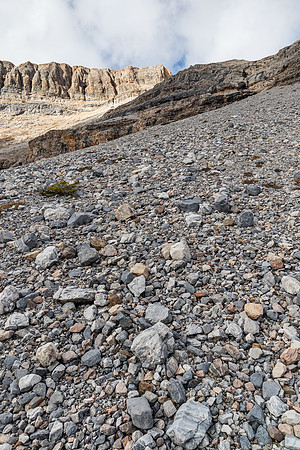 Ascending the scree cone above the treed buttress towards the first cliff band.