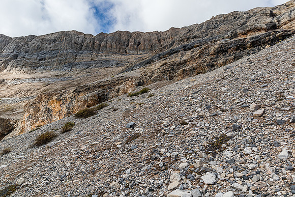 Ascending the scree cone above the treed buttress towards the first cliff band.