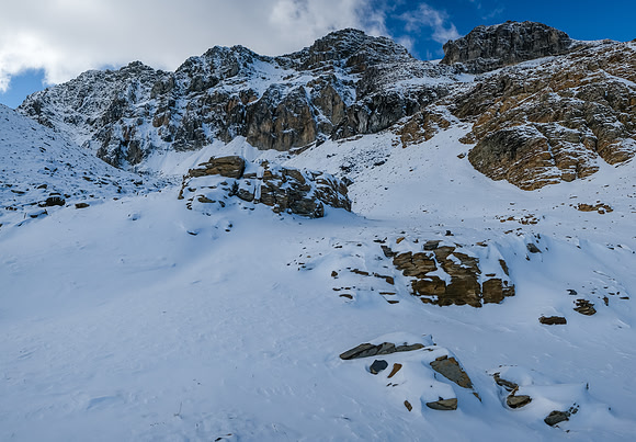 Route goes slightly left, than right up easy scree under dark cliffs at mid center.