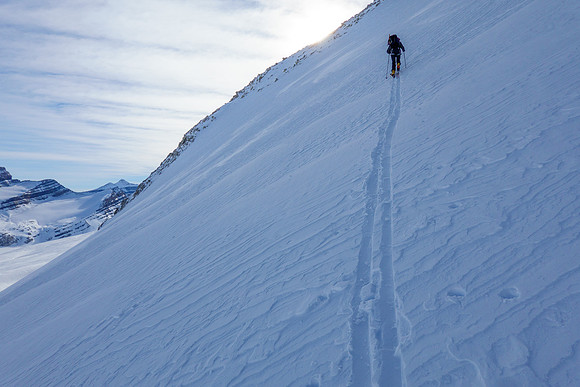 Skiing up the steep NE access slope to the south ridge above.