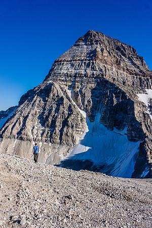 Kev heads down the slopes to the col, Assiniboine brooding above.