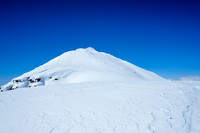 Still a ways to go after traversing the steep lower summit slopes.