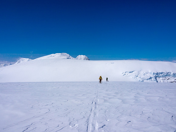 TJ and JW ski up Stutfield NE with Stutfield Peak, North Twin and Twins Tower poking up behind them