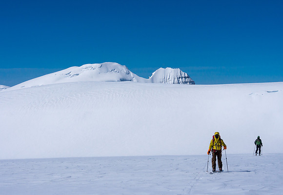 TJ and JW ski up Stutfield NE with Stutfield Peak, North Twin and Twins Tower poking up behind them