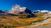 Looking back at Redoubt Mountain rising over Ptarmigan Lake and surrounded by a golden landscape.