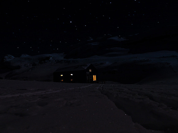 A cheery hut under a star-filled cold winter sky.