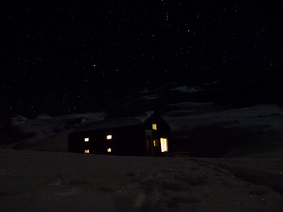 A cheery hut under a star-filled cold winter sky.