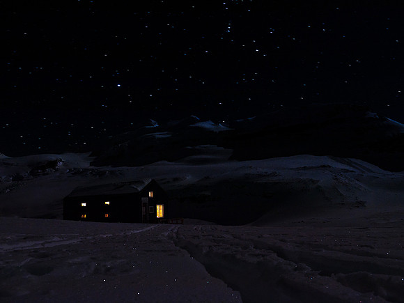 A cheery hut under a star-filled cold winter sky.