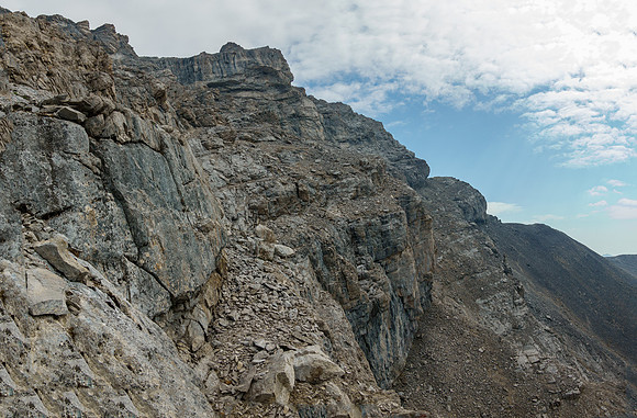 Traversing scree benches and ledges to the SE ridge along the upper south face.