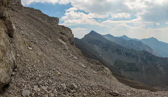 A wider scree bench just SW of the summit block leads to the ledge traverse.