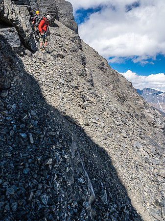 Descending the scree bench under the summit block rappel.