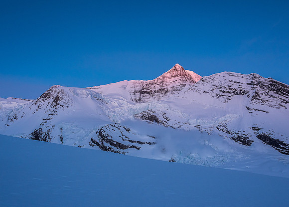 Mount Robson catches alpine glow as an ice avalanche thunders down the Robson Cirque in the foreground!