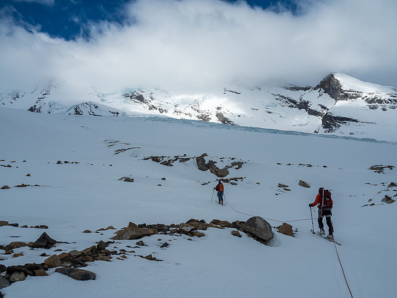 The handrail of rock just ahead of Ben assists in skiing a safe route up under the Extinguisher Tower (OOS at left) and avoiding the icefall visible to our right.