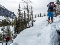 Ben skis up a narrow switchback on the trail above me while Mike completes his morning yoga session on the bridge at left.