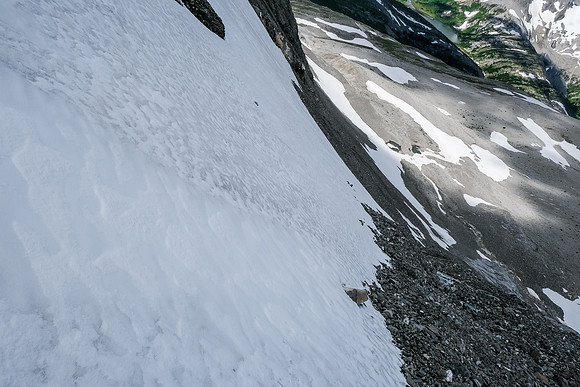 Views down the snow slope to the ledge. Exposed to serious rockfall from the false summit.