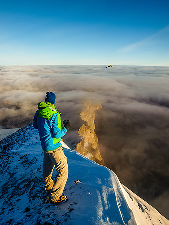 Vern on the summit with the cliffs towards Recondite showing up through clouds.