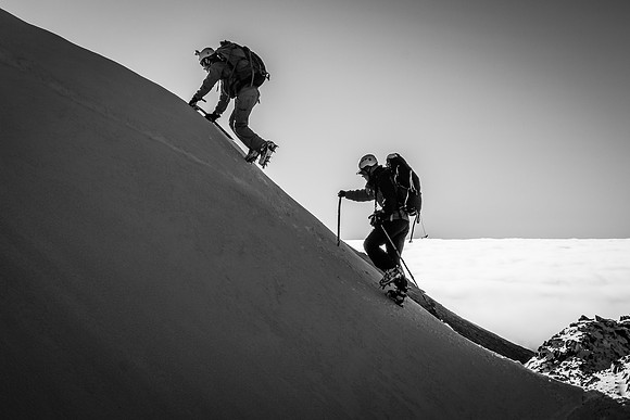 Ben and Steven climb up a short, icy slope to another arete.