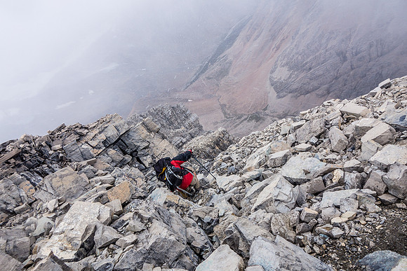 Descending the summit block in a snow squall. Note the loose rocks and steep slabby terrain.