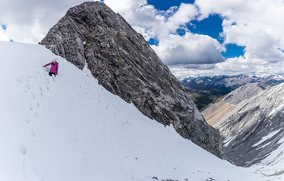 Joanna is waist deep on the cornice with the crux behind her.
