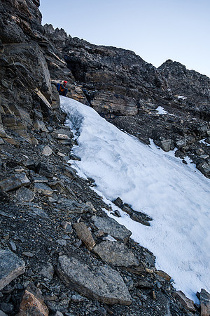 Traversing the southwest face on a mixture of snow, scree and boulders.