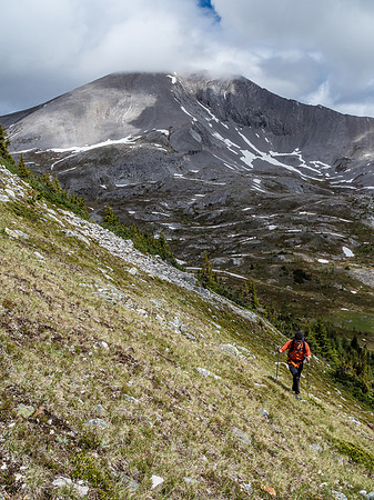 Phil ascends steep grassy slopes with the summit of Fatigue Mountain still in the clouds behind him.