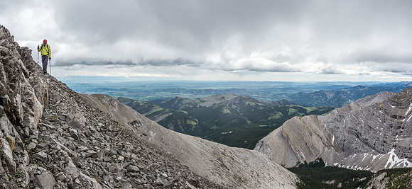 Wietse traverses around the first pinnacle on the ridge with stormy skies over the prairies behind him.