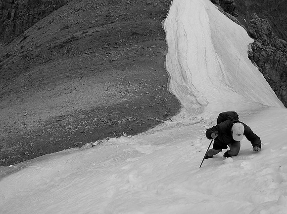 Sonny climbs up steep snow to the false summit from the true one.
