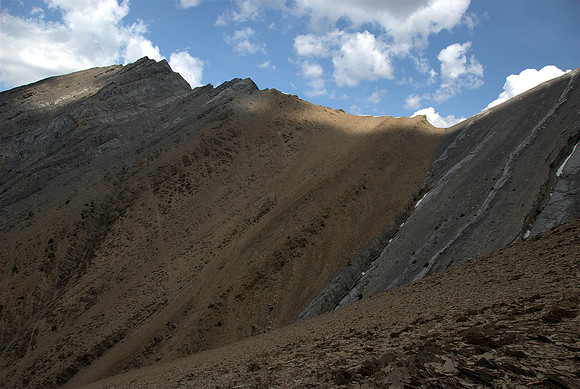 The tallest point is the one at the upper left but you should first go to the one on the upper right and then traverse along the ridge.